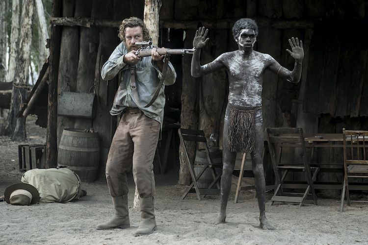 [L-R] Simon Baker as Travis and Jacob Junior Nayinggul as Gutjuk in the adventure/drama film, HIGH GROUND, a Samuel Goldwyn Films release. Photo Courtesy of Samuel Goldwyn Films.