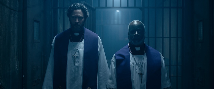 (L-R) Will Beinbrink as Father Peter Williams and Joseph Marcell as Father Michael Lewis in the horror film, THE EXORCISM OF GOD, a Saban Films release. Photo courtesy of Saban Films.